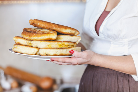 Women's hands holding a plate of fried pies, stacked, side viewの写真素材