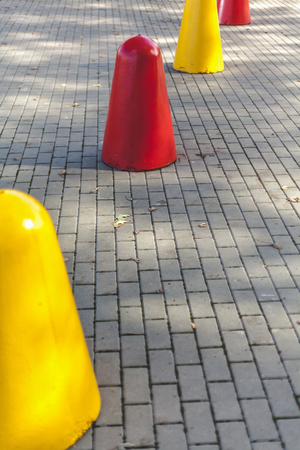 number of red and yellow cast-iron pedestals for parking vehicles stands on the sidewalk tile