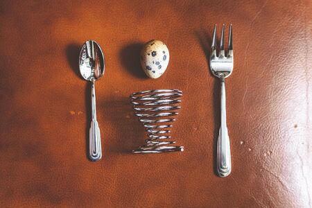 Egg quail, spiral stand, fork, spoon lie on the brown skin. Set for dietary breakfastの写真素材