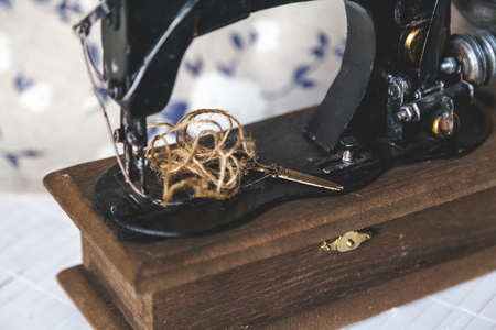 Still life with a sewing machine. Vintage sewing machine, scissors and a skein of threads closeup....