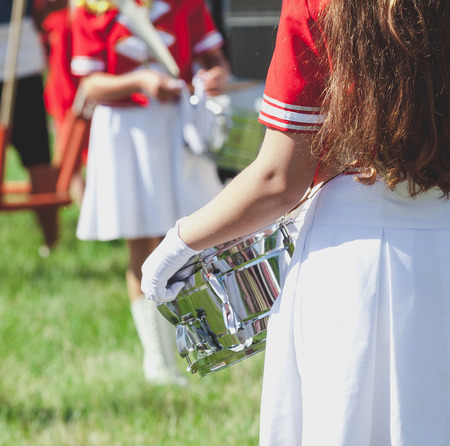 Girl with long flowing hair in uniform holding a shiny drum on a summer holidayの写真素材