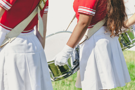 Girl with long flowing hair in uniform holding a shiny drum on a summer holidayの写真素材