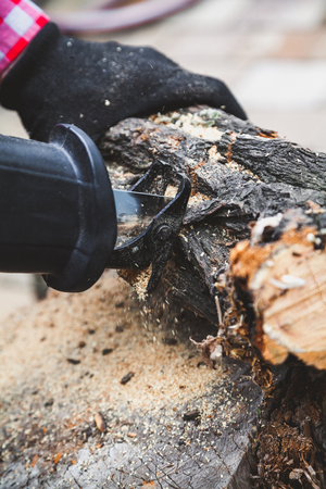 worker sawing a round piece of wood dry acacia reciprocating power saw. A gloved hand holding a piece of wood. Close-up. Side view
の写真素材
