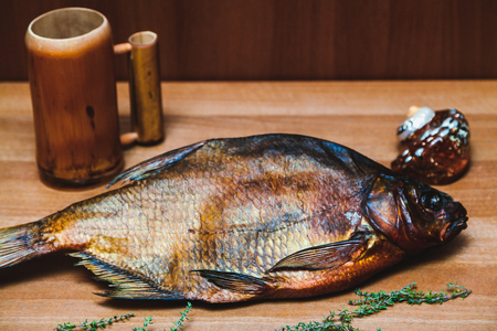 large dried smoked bream on brown parchment paper. Next to the wooden beer mug and shellfish
の写真素材