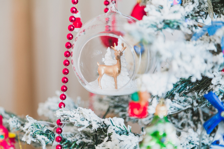 original Christmas tree toy is a brown deer inside a transparent ball weighing on a Christmas tree. Near the red garland
の写真素材