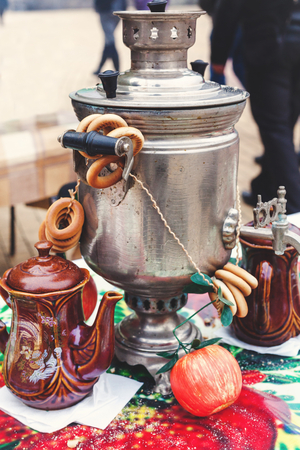 Russian set for tea. Iron samovar, clay pots, and bundle bagels standing on colorful tablecloth on a traditional Slavic holiday Maslenitsa
の写真素材