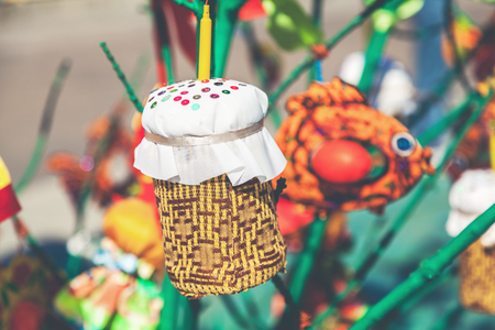 handmade toys as Easter cake with a candle weighs on a tree branch in spring day
