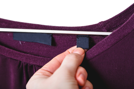 hand holds a patch on a burgundy sweater. He weighs on a wooden hanger on a white background
の写真素材