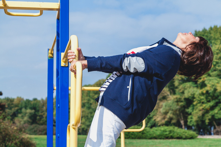 Physical education in retirement. A nice active elderly woman is engaged in health gymnastics on the street simulators of a sports ground.
の写真素材