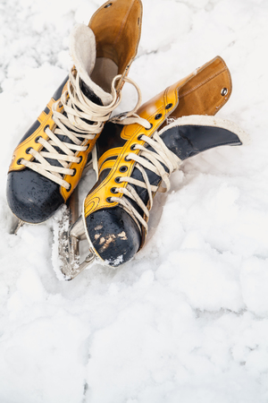 Skates in the snow. Two leather boots of yellow and black with skates lie on white loose snow
の写真素材
