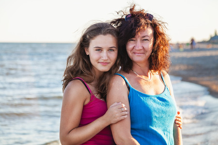 Family idyll. Adult beautiful daughter hugs a pretty mother on the beach by a summer day
の写真素材