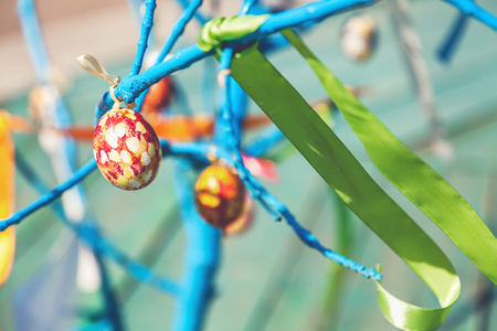 Painted Easter egg hanging on a tree branch blue outdoors

