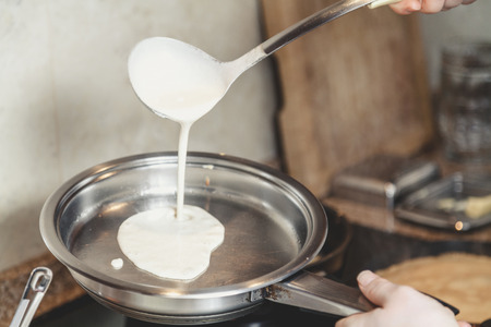 Cooking pancakes. On a round skillet liquid dough from the ladle is poured
の写真素材