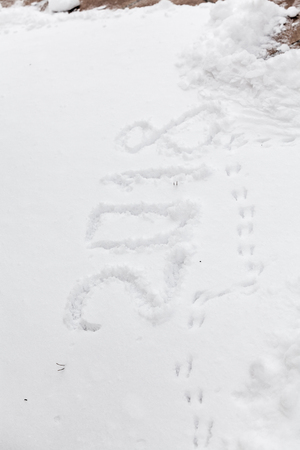New year in the street. 2018 written on white snow. Nearby there are footprints from the paws of a birdの写真素材