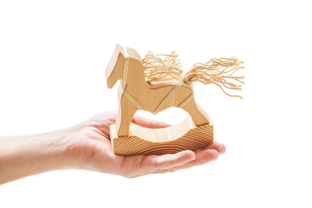 Wooden toy rocking. Hand holds a horse figure with a mane and tail of ropes on a white backgroundの写真素材