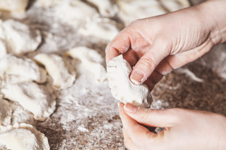 woman hands are making a damp dumpling. On the granite table top some raw dumplings in flour lieの写真素材