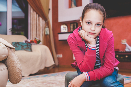 Young girl in a red sweater sitting in a cozy roomの写真素材