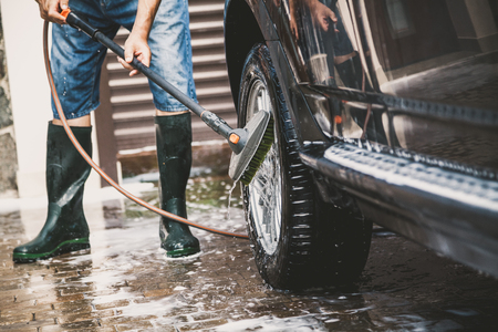 man in rubber boots washes a black car with a special brush on a long handle
の写真素材