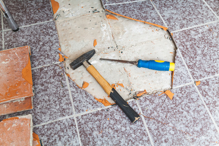 Dismantle the floor tiles. The chisel and the hammer lie on the floor free of tiles. Around the torn square tileの写真素材