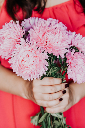 girl in a red dress is holding a bouquet of pink chrysanthemumsの写真素材