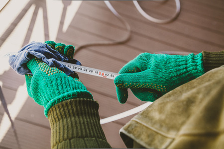 Care of the tool. Hands in green gloves wipe with a rag metal tape long measuring roulette