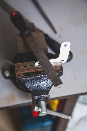 Metal flat corner with three holes in the bench screw is fixed. On top is a flat file. View from above
の写真素材