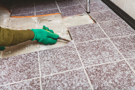 dismantling of tile. Hands in green working gloves undermine the broken tile with a chisel.
の写真素材