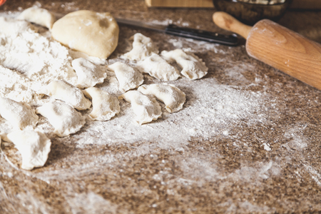 marble table top lie raw dumplings and a piece of dough in white flour. Next to the wooden rolling pin and knife
の写真素材
