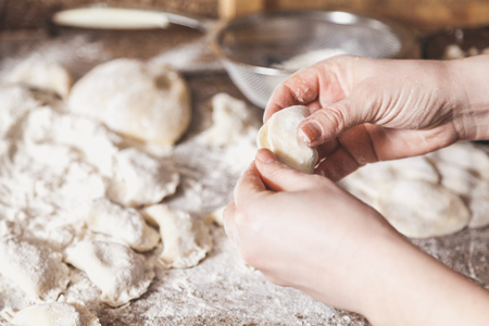 woman hands are making a damp dumpling. On the granite table top some raw dumplings in flour lie
の写真素材