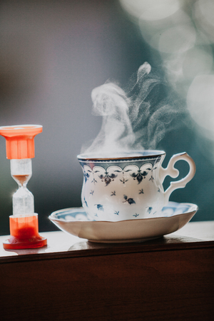 Time to drink tea. A neat cup for tea with a blue pattern and a saucer stand on wooden rails. Near...