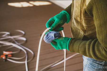 Care of the tool. Hands in green gloves wipe with a rag metal tape long measuring rouletteの写真素材