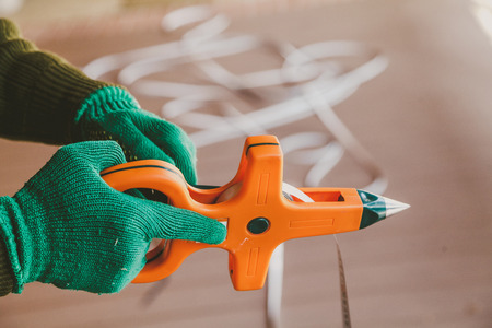 Hands in green gloves wind a steel band on an orange geodetic rouletteの写真素材
