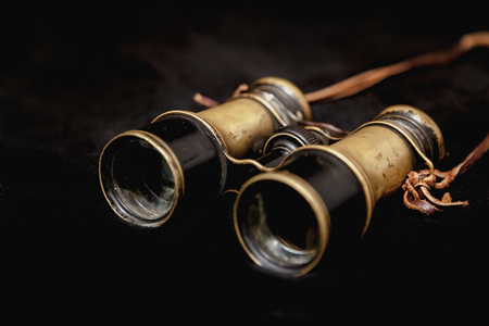 Vintage metal binoculars with a leather strap on a black backgroundの写真素材