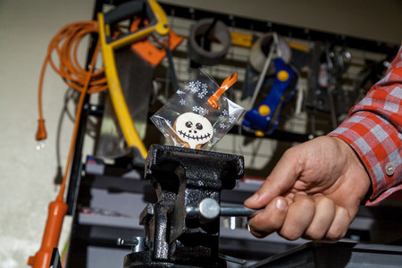 Halloween in the workshop. Cookies for Halloween in a transparent package clamped in a vise. Hand...