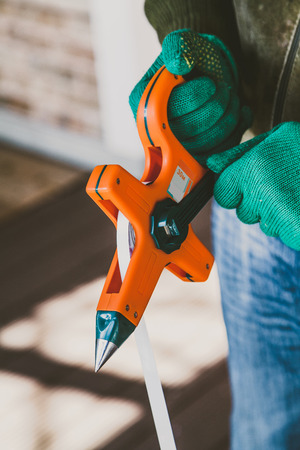 Hands in green gloves wind a steel band on an orange geodetic rouletteの写真素材