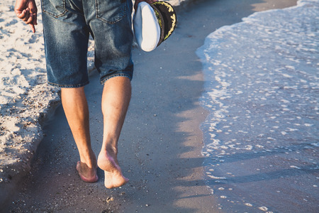 Man in shorts walking on sea beach summer eveningの写真素材