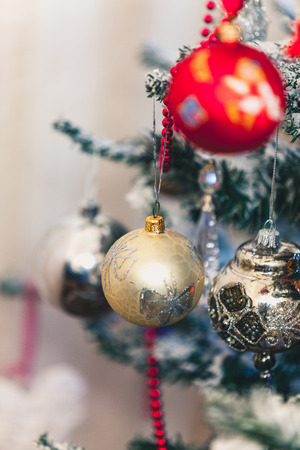 Cute New Year toy yellow ball with a painted butterfly hanging on a green Christmas tree branchの写真素材