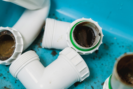 Details of the disassembled sanitary siphon lie in a blue basin close-up. inside, there is a sediment and a patch of dirt. View from aboveの写真素材