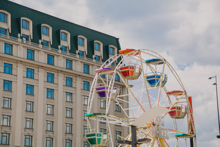 City attraction. Ferris wheel on the background of a modern building and the sky with white cloudsの写真素材