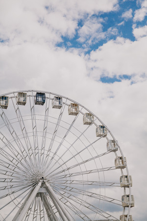Viewing attraction. Cabins on the Ferris wheel against the blue sky with white cloudsの写真素材