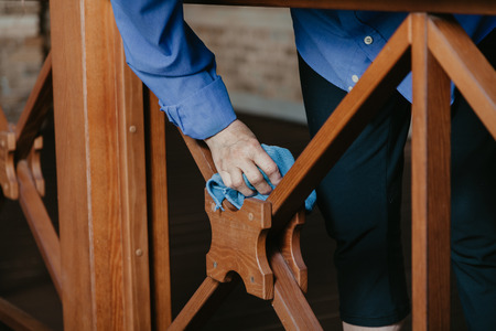 We do cleanliness. Woman hands wipe the wooden fence on the terrace with a rag