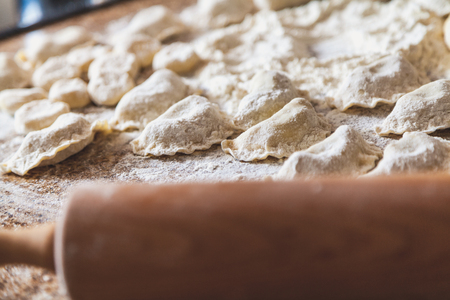 On the marble table top are raw dumplings in white flour. Next to the wooden rolling pinの写真素材