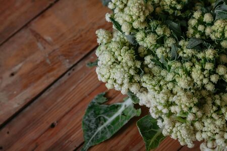 Autumn still life. Cauliflower head on the old planed wooden boards closeup
