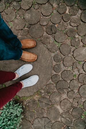 Summer romantic date. The legs of a woman and a man stand on a path made from cropped round arches. View from aboveの写真素材