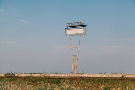 Metal sign of the passenger platform of the railway against the blue sky. In the foreground green grassの写真素材