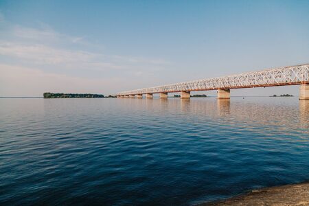 Transport bridge on concrete piers across a wide river. View from the shore