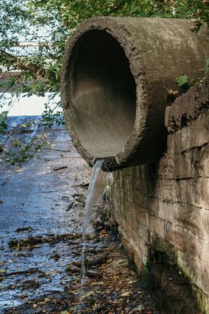 Concrete pipe storm drainage system close-up. A stream of water flows out of the pipeの写真素材