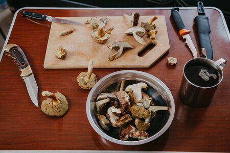 Still life with mushrooms. Sliced ââmushrooms and a knife are lying on a wooden board. Next on the table is metal dishesの写真素材
