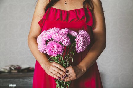 girl in a red dress holding a bouquet of pink chrysanthemumsの写真素材