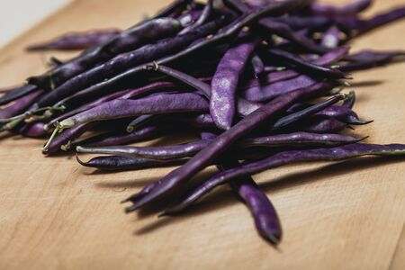 Beautiful pods of purple bean lie on a wooden boardの写真素材